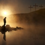 Three Crosses and Silhoutted Person in Prayer at Sunrise